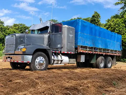 Camión tándem con plataforma de Transportes Treinta, con la carga cubierta con lona